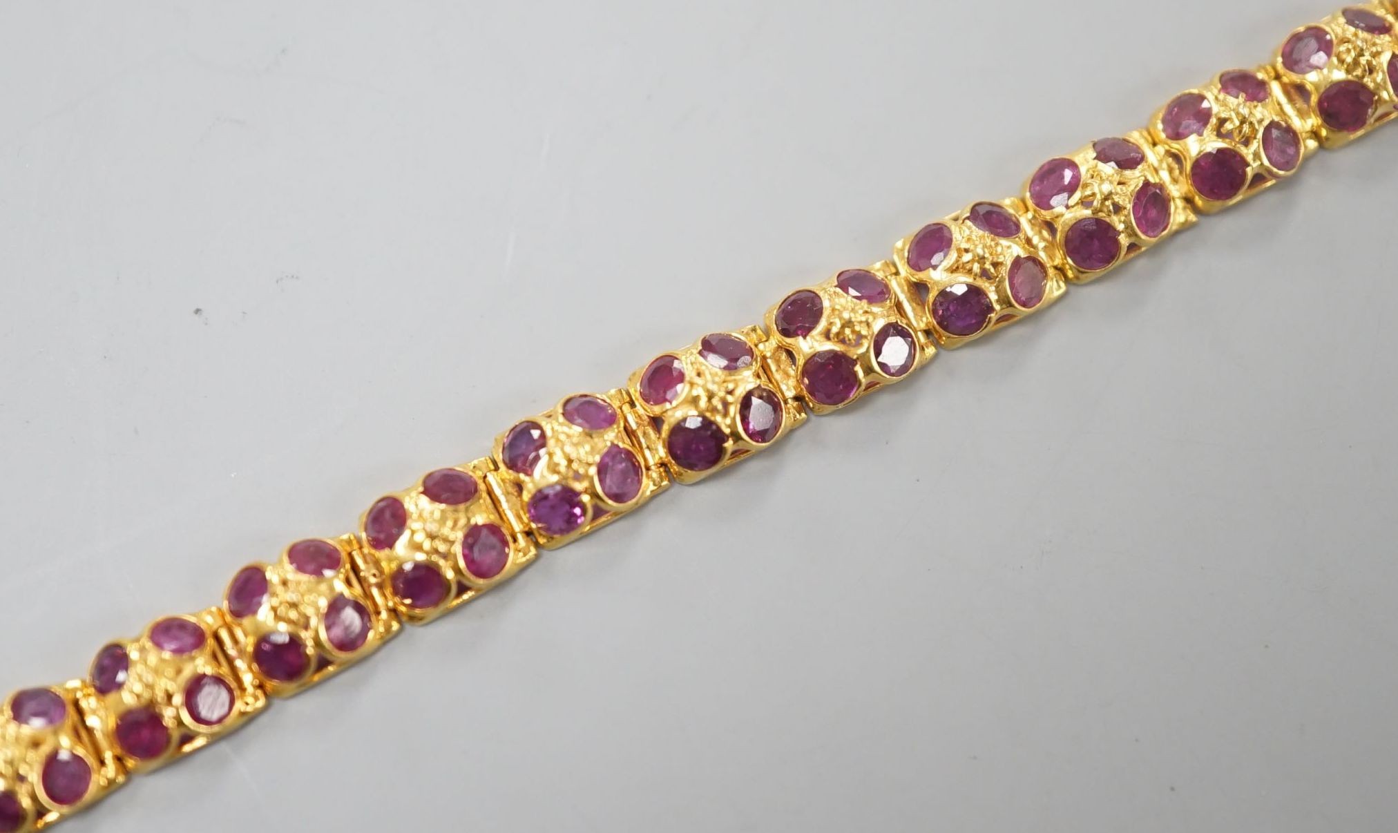 A modern Thai yellow metal and pink gem set cluster bracelet, 17cm, gross weight 8.7 grams.